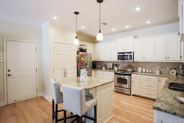 29 Taylor Park Loop, Little Rock, AR 72211 - kitchen featuring appliances with stainless steel finishes, light wood-type flooring, ornamental molding, a kitchen breakfast bar, and backsplash