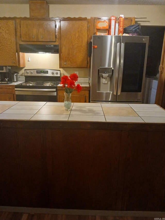 320 S Lewis St, Mineral Sprs, AR 71851 - kitchen featuring stainless steel appliances, tile counters, under cabinet range hood, and brown cabinets