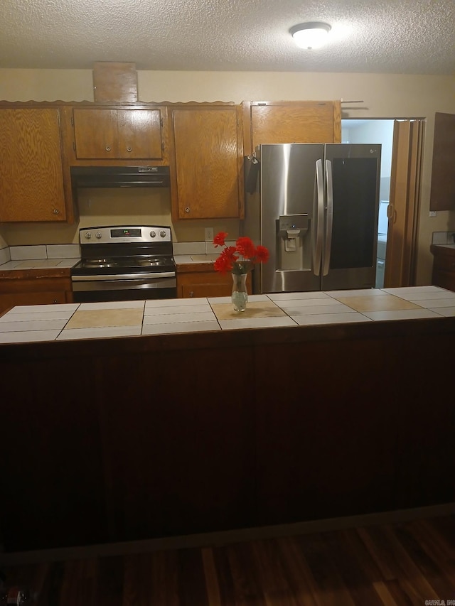 320 S Lewis St, Mineral Sprs, AR 71851 - kitchen featuring stainless steel appliances, tile counters, brown cabinetry, exhaust hood, and dark wood finished floors