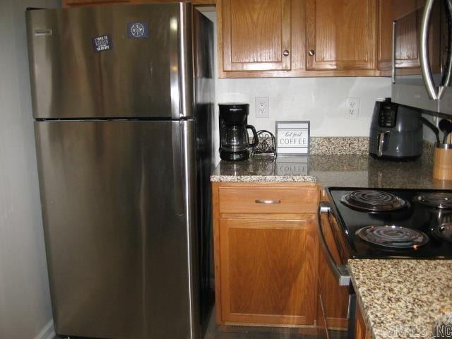 601 Dave Creek Pkwy Unit 107, Fairfield Bay, AR 72088 - kitchen with stainless steel appliances, brown cabinetry, and light stone countertops