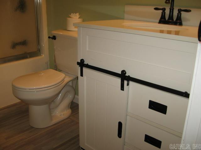 601 Dave Creek Pkwy Unit 107, Fairfield Bay, AR 72088 - full bathroom with vanity, wood finished floors, and enclosed tub / shower combo