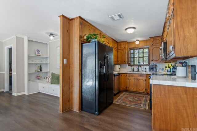 1920 W Arch Ave, Searcy, AR 72143 - kitchen with appliances with stainless steel finishes, dark wood-type flooring, brown cabinetry, decorative backsplash, and crown molding