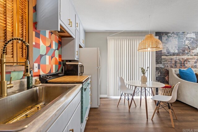 1920 W Arch Ave, Searcy, AR 72143 - kitchen with dark wood-style floors, white cabinetry, stainless steel microwave, and freestanding refrigerator