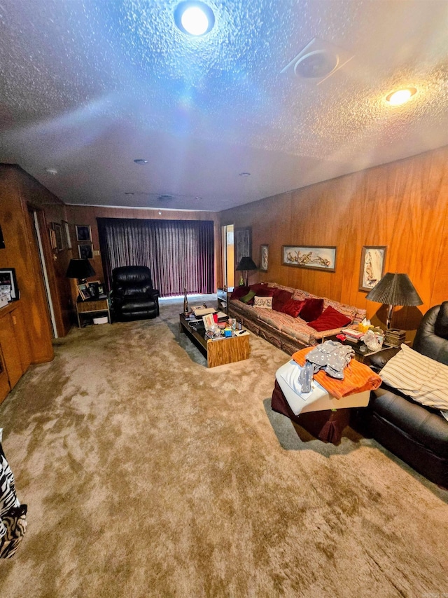 carpeted living area featuring wooden walls and a textured ceiling