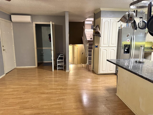 kitchen with a wall unit AC, light wood-style flooring, a textured ceiling, ornamental molding, and stainless steel fridge with ice dispenser