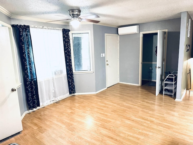 unfurnished bedroom featuring a wall mounted air conditioner, light wood-style floors, ornamental molding, a textured ceiling, and ceiling fan