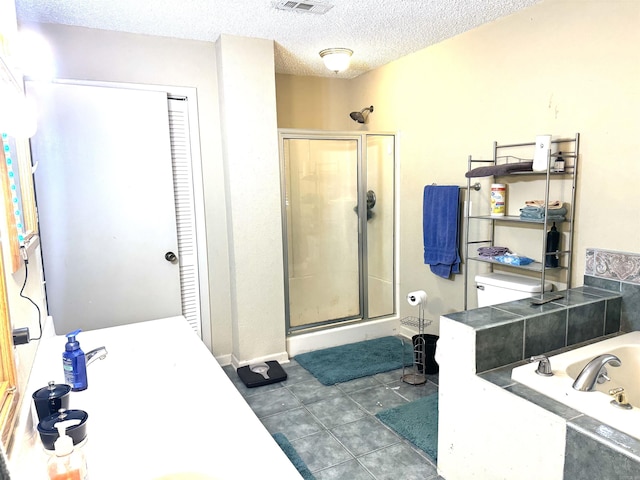 full bath featuring a shower stall, a garden tub, a textured ceiling, and a closet