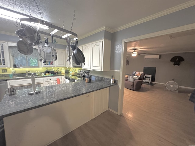 kitchen with electric stove, a wall mounted air conditioner, wood finished floors, dark stone counters, and crown molding