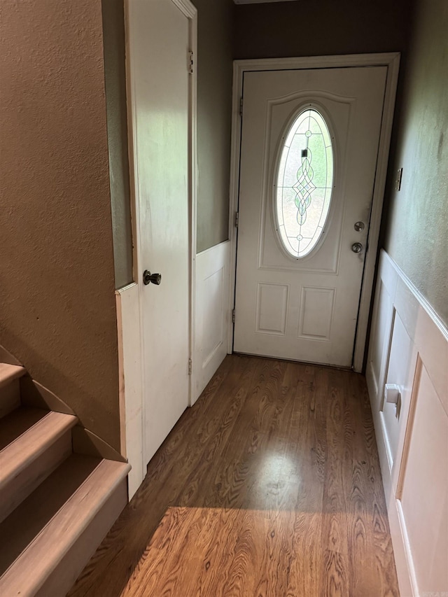 entryway featuring wood finished floors, a textured wall, stairs, and a wainscoted wall