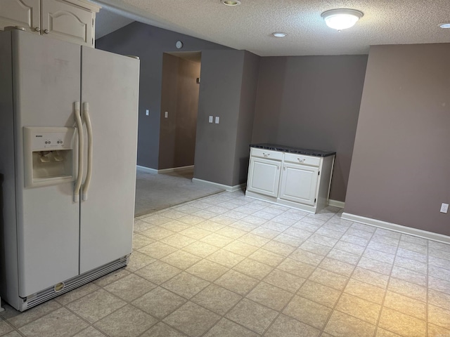 1008 Fox Ridge Dr, Benton, AR 72019 - kitchen with white fridge with ice dispenser, a textured ceiling, white cabinetry, dark countertops, and light flooring
