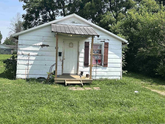768 E Locust, Piggott, AR 72454 - view of front of house featuring a front lawn, a metal roof, an outdoor structure, and a standing seam roof