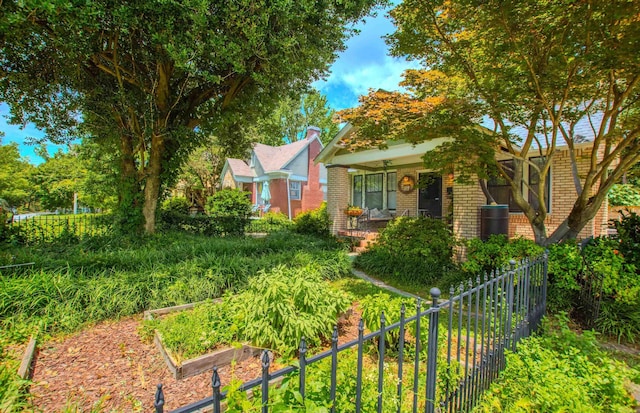 319 W G Ave, North Little Rock, AR 72116 - view of property hidden behind natural elements featuring brick siding, a garden, and covered porch