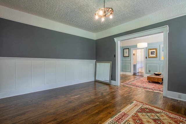 319 W G Ave, North Little Rock, AR 72116 - empty room with a textured ceiling, a decorative wall, a chandelier, wood finished floors, and wainscoting