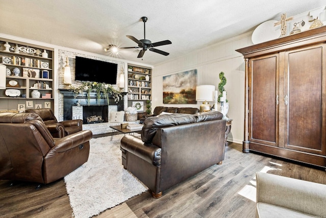 520 E 8th St, Lonoke, AR 72086 - living area featuring a ceiling fan, a fireplace, a textured ceiling, wood finished floors, and built in shelves