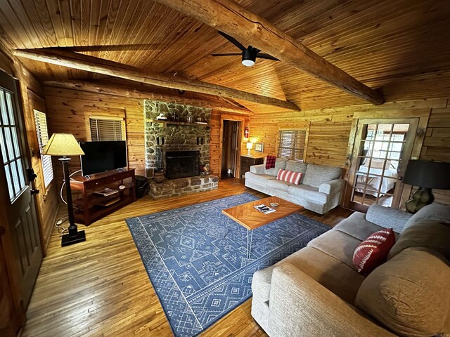 410 S Riverview Ln, Mountain View, AR 72560 - living room featuring a wood ceiling with exposed beams, wooden walls, a ceiling fan, hardwood / wood-style floors, and a stone fireplace