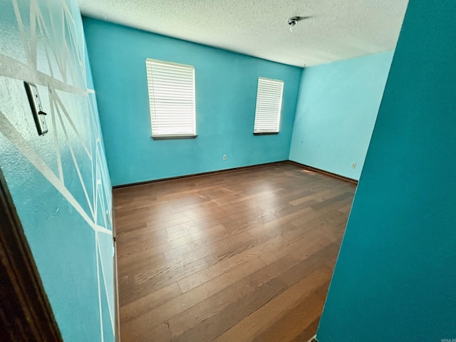 empty room with hardwood / wood-style floors and a textured ceiling