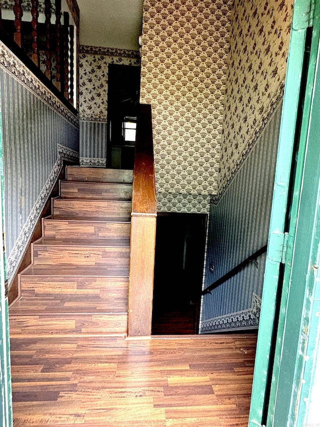 stairway featuring wallpapered walls and wood finished floors