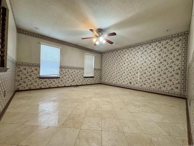 spare room with a ceiling fan, wallpapered walls, a textured ceiling, and crown molding