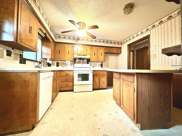 kitchen featuring white appliances, a ceiling fan, under cabinet range hood, wallpapered walls, and a textured ceiling