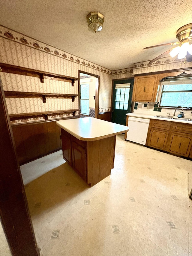 kitchen featuring dishwasher, wallpapered walls, brown cabinets, light countertops, and light flooring