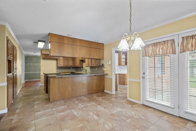 3905 Deer Dr, Benton, AR 72019 - kitchen with a peninsula, ornamental molding, a chandelier, brown cabinets, and hanging light fixtures