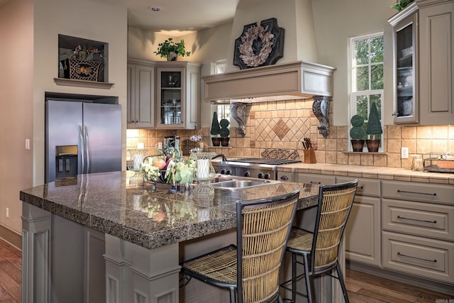 12 Cobblestone Way, Little Rock, AR 72223 - kitchen with stainless steel fridge, dark wood finished floors, a center island, a breakfast bar area, and glass insert cabinets
