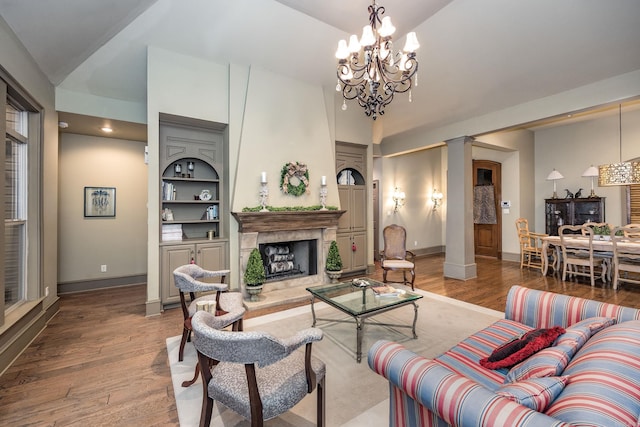 12 Cobblestone Way, Little Rock, AR 72223 - living room featuring ornate columns, a fireplace, wood finished floors, a chandelier, and high vaulted ceiling