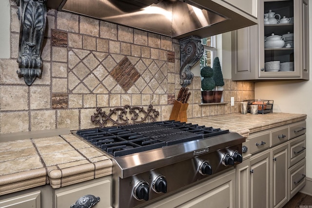 12 Cobblestone Way, Little Rock, AR 72223 - kitchen featuring stainless steel gas stovetop, tile countertops, tasteful backsplash, and glass insert cabinets