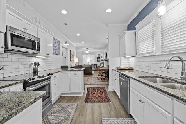 100 Melrose Dv, North Little Rock, AR 72114 - kitchen with stainless steel appliances, white cabinets, wood finished floors, open floor plan, and tasteful backsplash