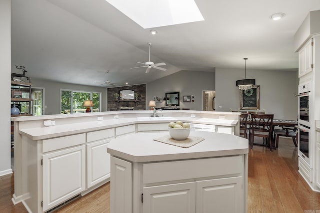 96 San Sebastian Way, Hot Springs Village, AR 71909 - kitchen featuring a center island with sink, light countertops, light wood-type flooring, and vaulted ceiling
