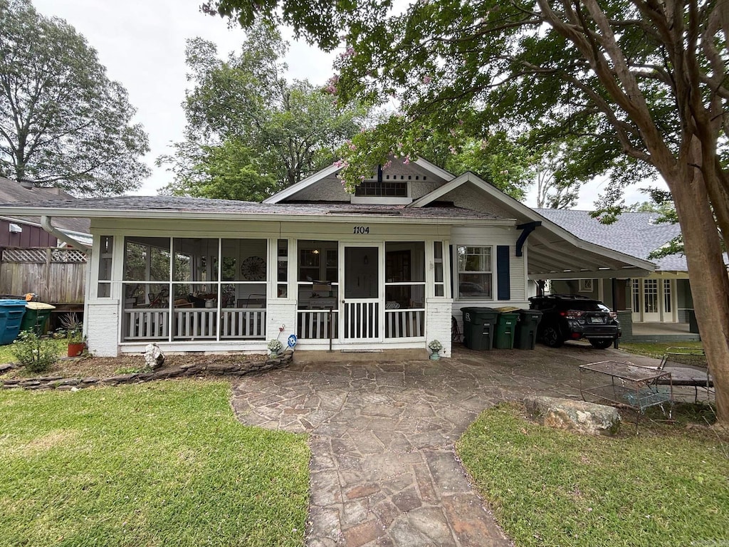 1104 N Monroe St, Little Rock, AR 72205 - view of front of house featuring a sunroom, a carport, roof with shingles, and brick siding