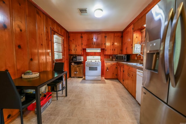 3215 Edgewood Rd, El Dorado, AR 71730 - kitchen featuring stainless steel appliances, exhaust hood, brown cabinets, wooden walls, and light floors