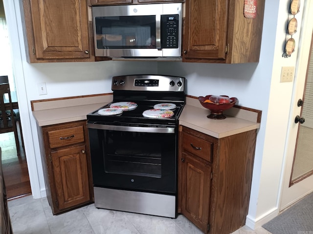 1402 Holmes Rd, Searcy, AR 72143 - kitchen with stainless steel microwave, range with electric stovetop, light countertops, and light tile patterned floors