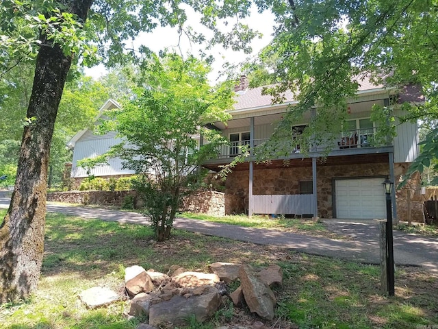 1402 Holmes Rd, Searcy, AR 72143 - obstructed view of property with stone siding, an attached garage, a chimney, and driveway
