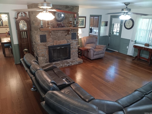 1402 Holmes Rd, Searcy, AR 72143 - living room featuring ceiling fan, wood finished floors, a stone fireplace, and wainscoting