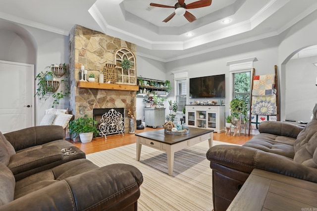 3051 Mount Mcgregor Dr, Benton, AR 72019 - living area featuring a stone fireplace, ceiling fan, arched walkways, crown molding, and a tray ceiling