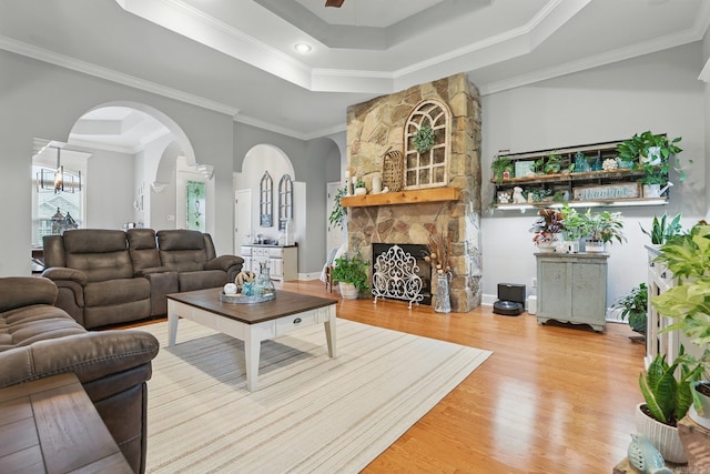 3051 Mount Mcgregor Dr, Benton, AR 72019 - living area featuring a tray ceiling, arched walkways, wood finished floors, a stone fireplace, and crown molding