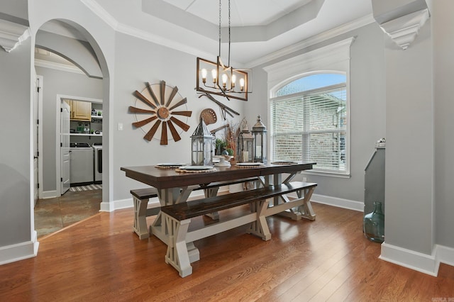 3051 Mount Mcgregor Dr, Benton, AR 72019 - dining area with wood finished floors, a tray ceiling, washing machine and dryer, arched walkways, and a chandelier