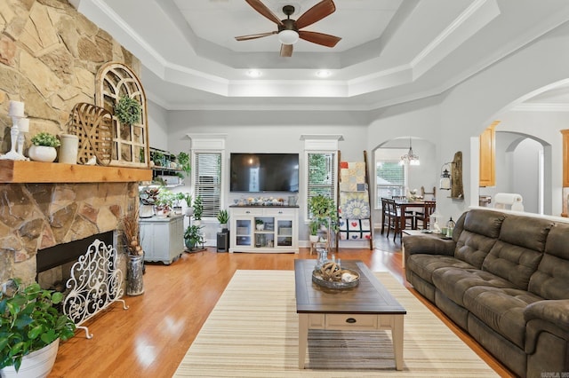 3051 Mount Mcgregor Dr, Benton, AR 72019 - living area featuring a stone fireplace, a ceiling fan, arched walkways, crown molding, and a tray ceiling