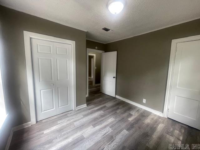 741 Macarthur Ave, Wake Village, TX 75501 - unfurnished bedroom with a textured ceiling, wood finished floors, and a closet