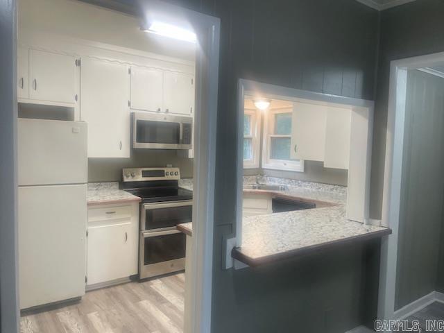 741 Macarthur Ave, Wake Village, TX 75501 - kitchen featuring appliances with stainless steel finishes, light countertops, white cabinets, and light wood finished floors