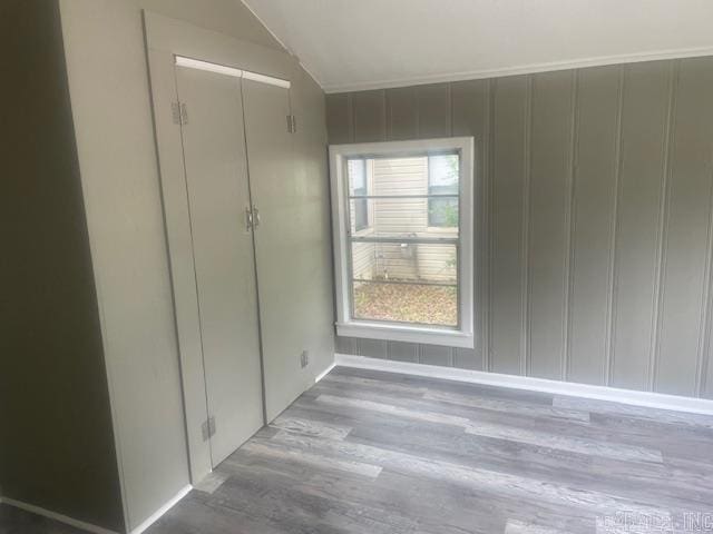 741 Macarthur Ave, Wake Village, TX 75501 - unfurnished bedroom with wood finished floors, vaulted ceiling, and a decorative wall