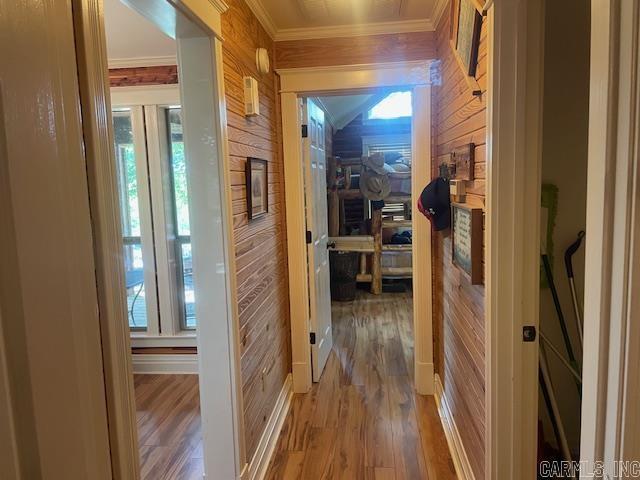 corridor with wood walls, crown molding, and wood finished floors