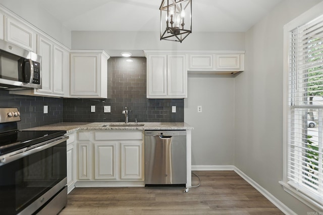 49 Kingsbridge Way, Little Rock, AR 72212 - kitchen featuring appliances with stainless steel finishes, backsplash, a chandelier, light wood-style flooring, and light stone countertops