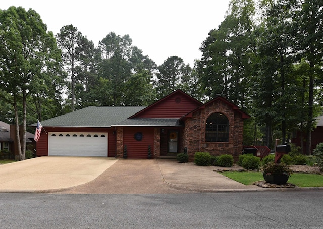 view of front facade with an attached garage, driveway, roof with shingles, and stone siding