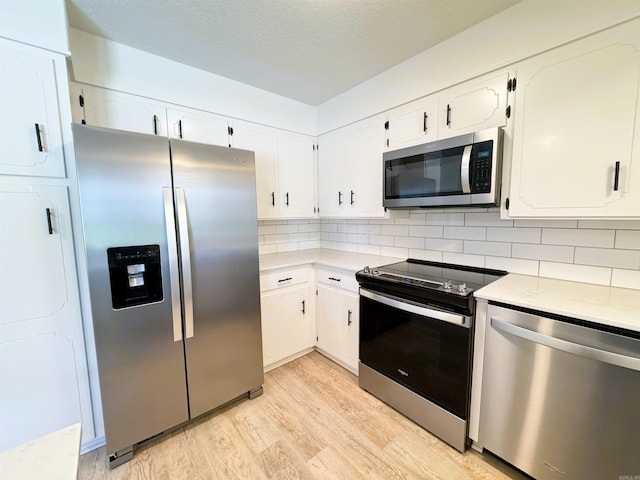 kitchen with stainless steel appliances, light wood-type flooring, decorative backsplash, light countertops, and white cabinetry