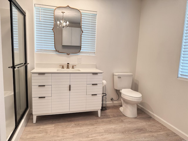bathroom with a chandelier, wood finished floors, vanity, and a shower with door