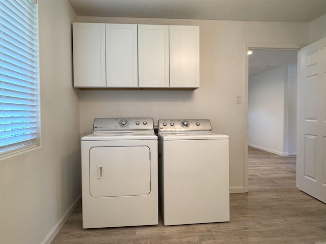 laundry area featuring cabinet space, independent washer and dryer, and light wood finished floors
