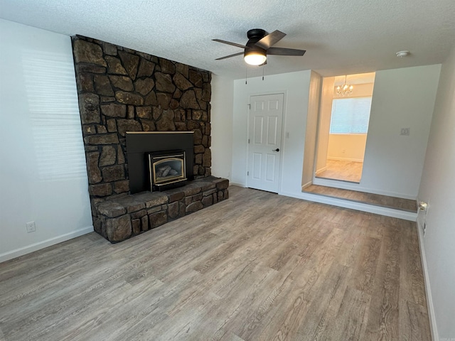 unfurnished living room featuring wood finished floors, a textured ceiling, a ceiling fan, and a chandelier
