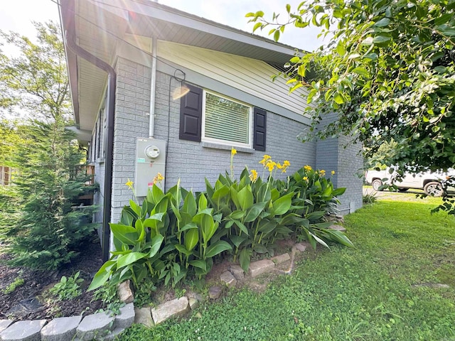 view of home's exterior with brick siding and a lawn